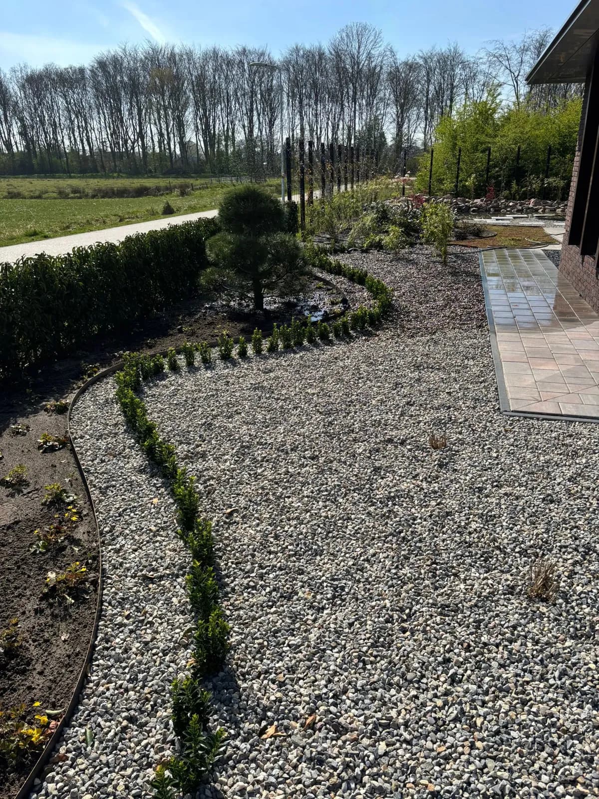 Grindstrook langs het huis in een rustige Japanse tuin met jonge beplanting bij een nieuwbouwwoning in Gorredijk