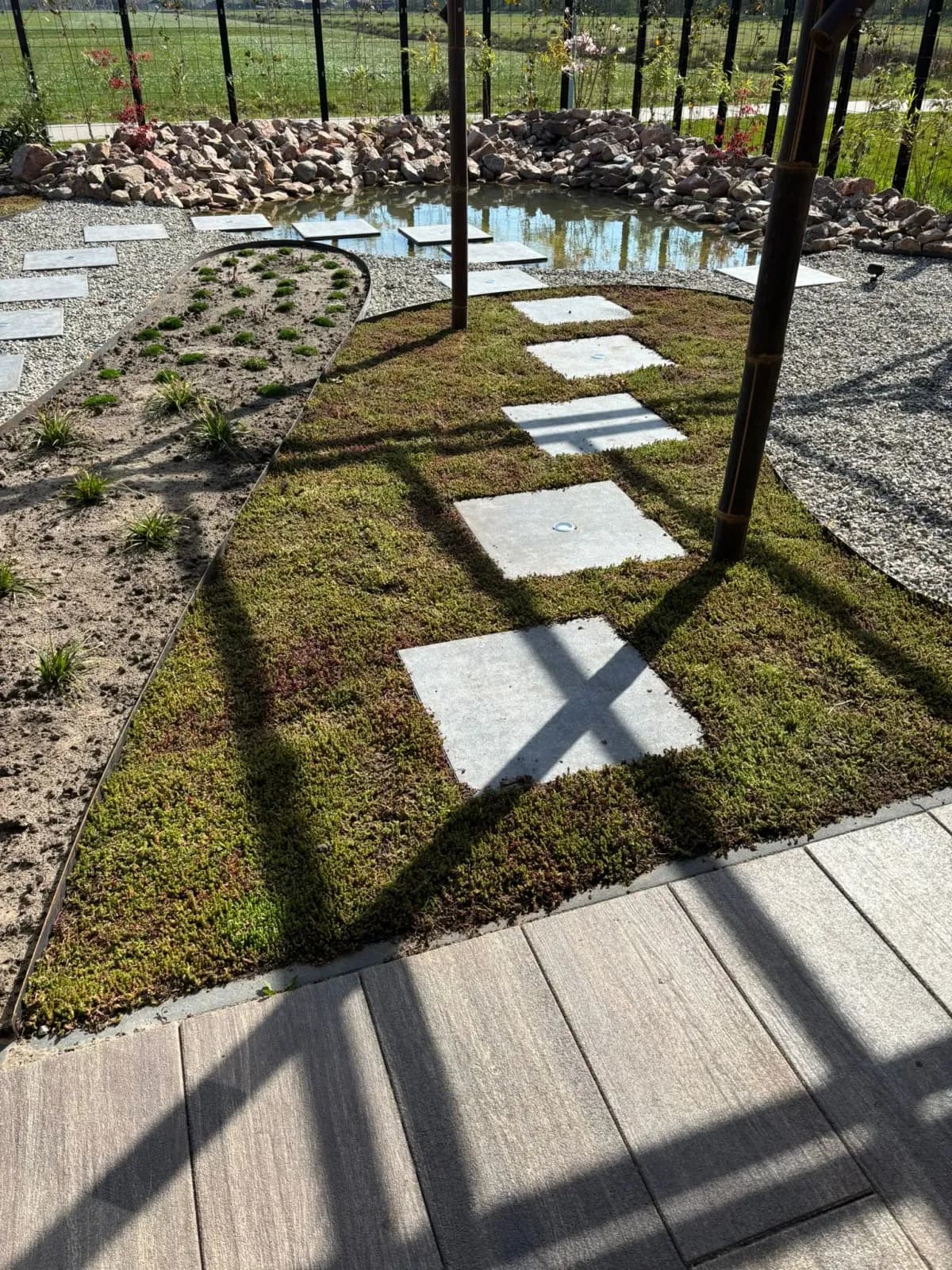Japanse tuin met betonnen stapstenen in sedum en grind, kleine beplanting en een vijver met rotsen bij een nieuwbouwwoning in Gorredijk