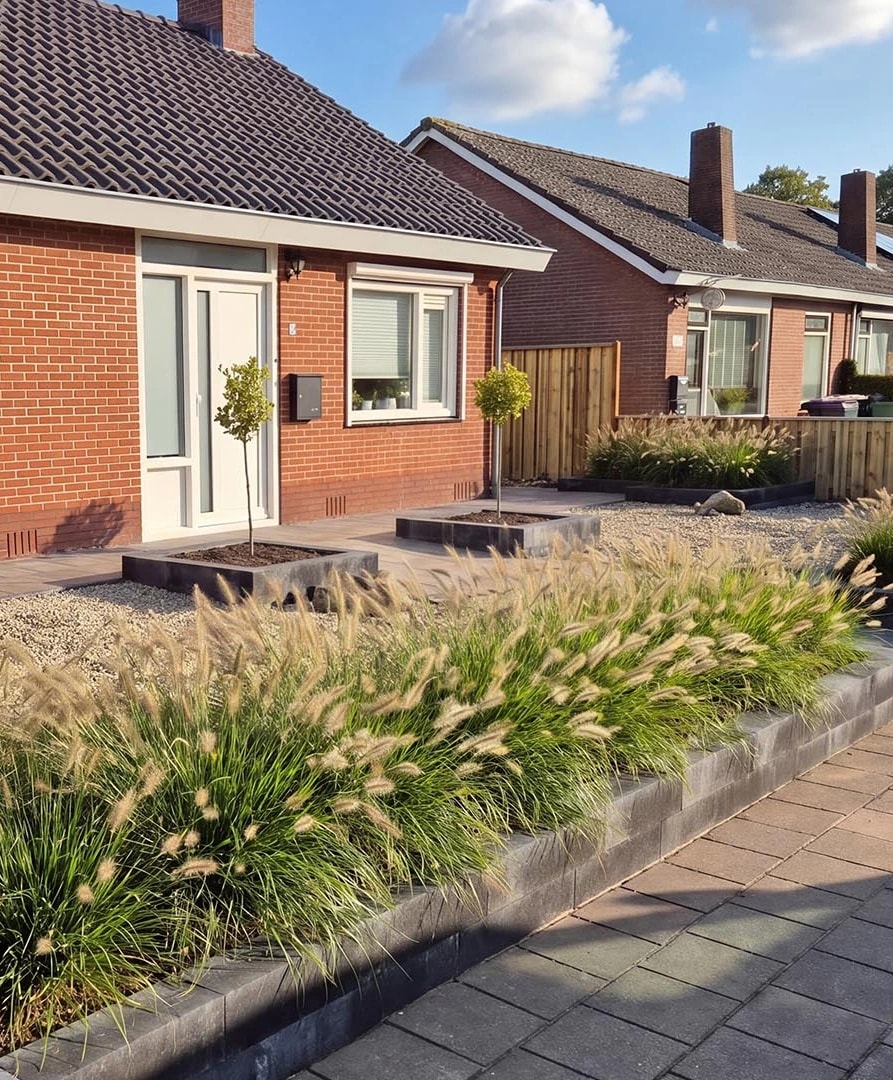 Voortuin in Harkema met siergrassen in verhoogde plantvakken van donkere betonband