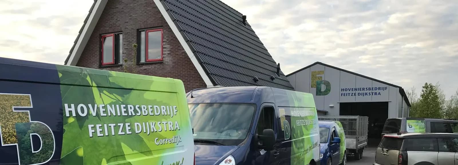 Bussen met het logo van Hoveniersbedrijf Feitze Dijkstra voor onze loods in Gorredijk, met hetzelfde logo op de gevel