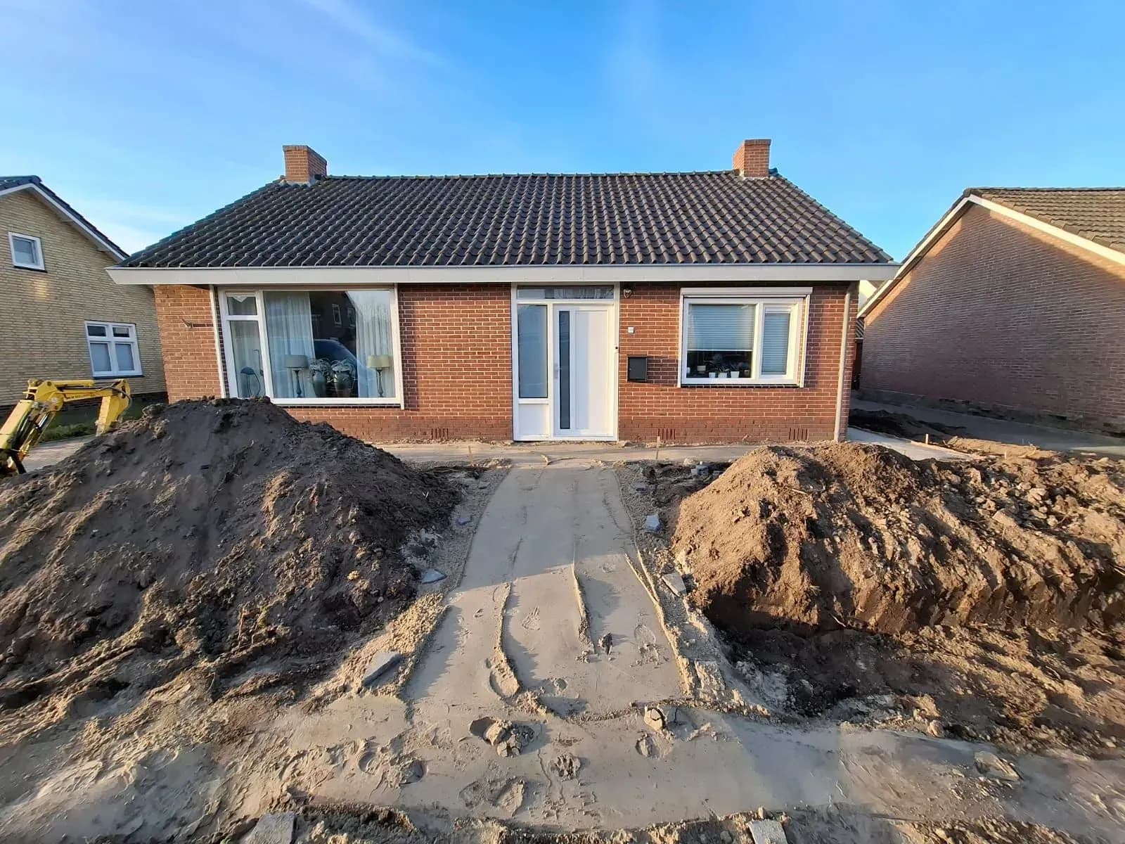 Hopen grond aan beide kanten van het pad naar de voordeur van een woning in Harkema, aan het begin van de renovatie van de voortuin